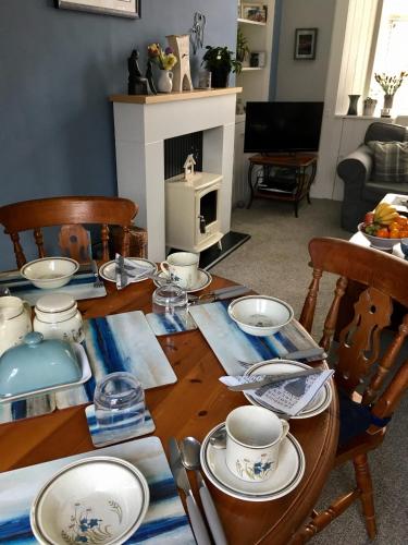 a dining room table with plates and cups on it at Alpine cottage in Crieff