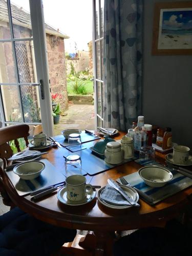 a wooden table with plates and dishes on it at Alpine cottage in Crieff