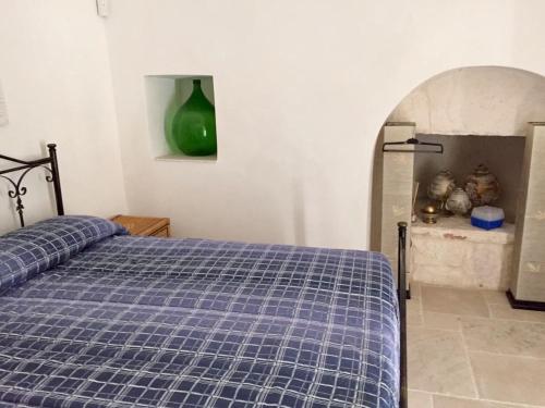 a bedroom with a bed with a blue checkered blanket at Trullo Grazioso Luxury in Ceglie Messapica