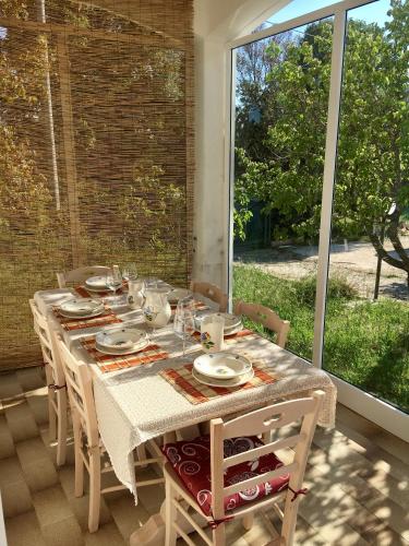 a dining room table with chairs and a large window at Trullo Grazioso Luxury in Ceglie Messapica