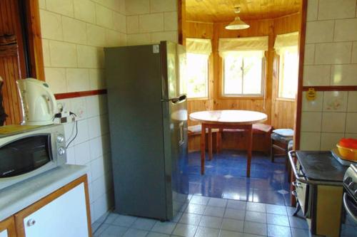 a kitchen with a refrigerator and a table in it at Saida Room Villarrica, arriendo habitaciones in Pucón