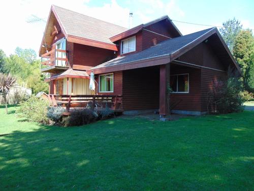 a wooden house with a grass yard in front of it at Saida Room Villarrica, arriendo habitaciones in Pucón