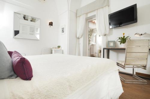 a white bedroom with a white bed and a tv at Casa Di Capri in Capri