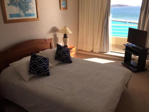 um quarto com uma cama com almofadas e uma janela em Apartamento en San Alfonso del Mar 3D-2B em Algarrobo