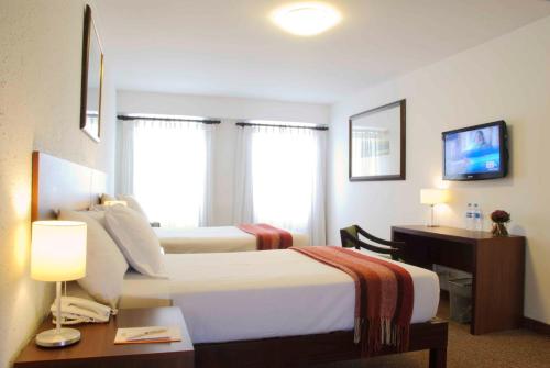a hotel room with two beds and a desk at Tierra Viva Arequipa Plaza in Arequipa