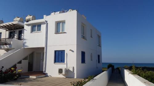 a white house with the ocean in the background at Periyiali Beach Sunset Suite A7 in Pervolia