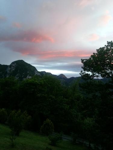 a sunset in the mountains with trees in the foreground at Casa Les Pedroses in Campiellos