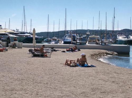 a group of people sitting on the beach near a marina at Apartments Gina in Trogir