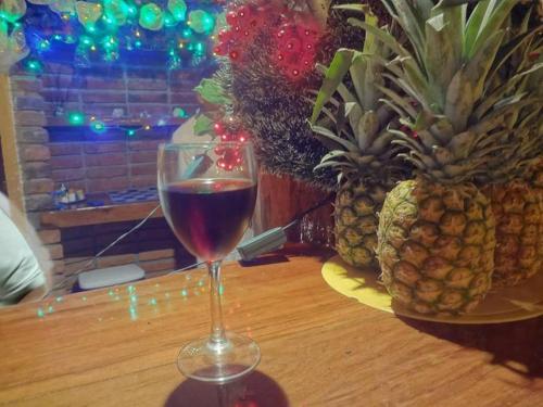 a glass of wine sitting on a table with pineapple at Hosteria Cumilinche in Same