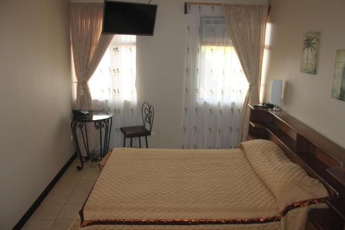 a bedroom with a bed and a television and a chair at Hotel Santa Maria Inn in Alajuela City