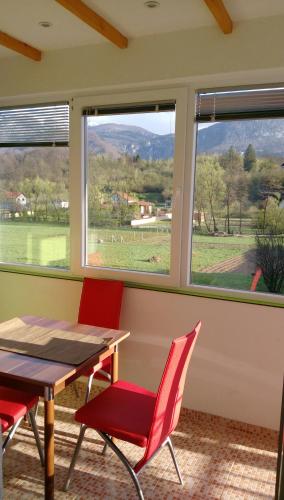 a dining room with red chairs and a table and windows at Apartment Mehi in Pazarić