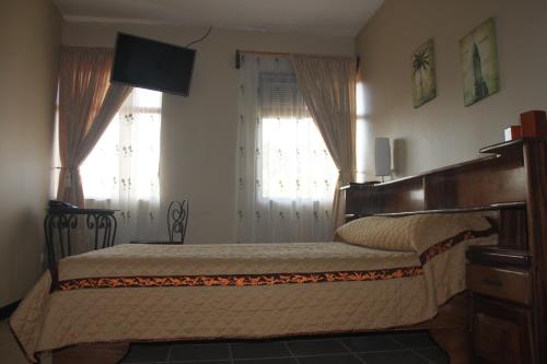 a bedroom with a bed and two windows at Hotel Santa Maria Inn in Alajuela City
