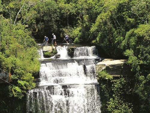 a group of people riding bikes on a waterfall at Blue Hill Hotel in Timbó