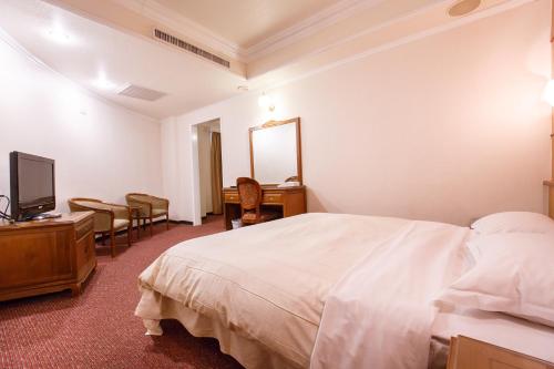 a bedroom with a bed and a desk and a television at Champion Hotel in Taipei