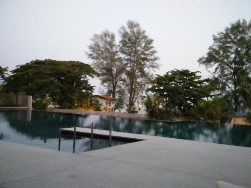 a swimming pool with trees in the background at By The Sea at Batu Ferringhi Penang in Batu Ferringhi