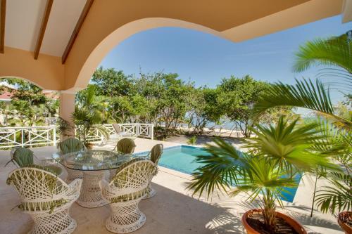 un patio con mesa, sillas y piscina en Naïa Resort and Spa, en Placencia Village