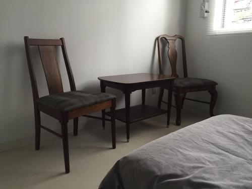 two chairs and a table in a room with a bed at ラナイ ホテルアンドドミトリー in Naha