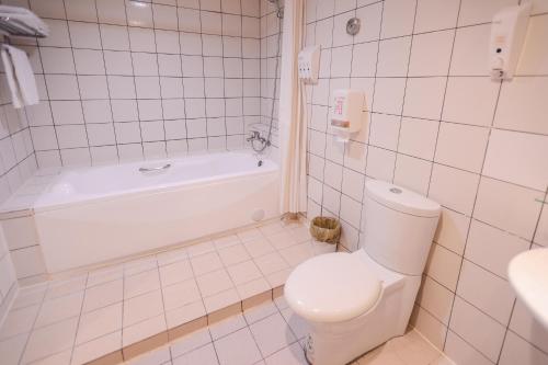 a white bathroom with a toilet and a bath tub at i-Deal Hotel in Taichung