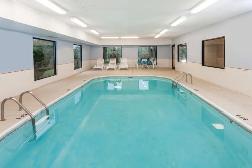 a swimming pool with blue water in a building at Super 8 by Wyndham Huntington in Huntington