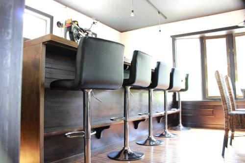 a row of black bar stools in a room at Nangoku Lodge Booya in Onna