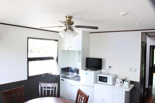 a kitchen with a table and a ceiling fan at Nangoku Lodge Booya in Onna