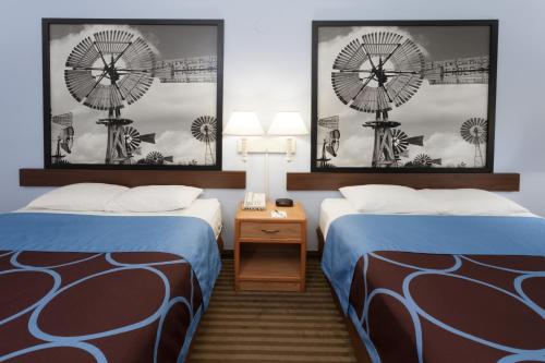 a hotel room with two beds and two clocks at Super 8 by Wyndham Huntington in Huntington