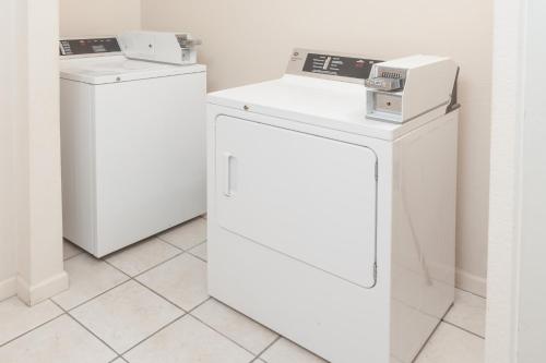 three white washers and dryers in a room at Super 8 by Wyndham Huntington in Huntington