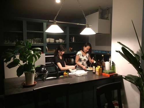 two women standing in a kitchen preparing food at ラナイ ホテルアンドドミトリー in Naha