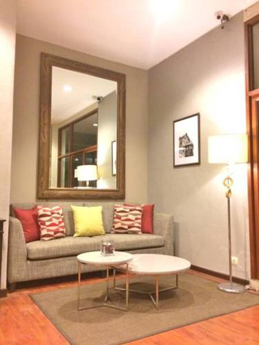 a living room with a couch and a mirror at Asoke Residence Sukhumvit by UHG in Bangkok