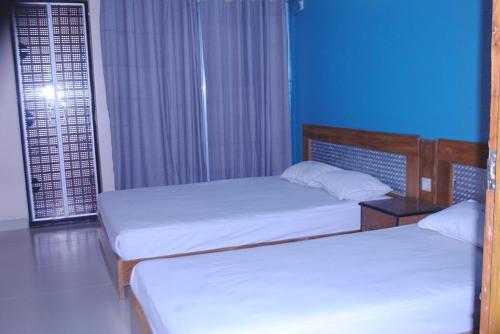 2 camas individuales en una habitación con paredes azules en Shopno Bilash Holiday Suites, en Cox's Bazar
