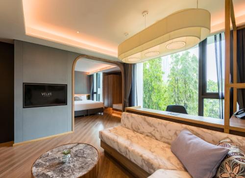 a living room with a couch and a large window at Volve Hotel Bangkok in Bangkok