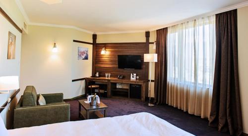 a hotel room with a bed and a desk with a television at Hot Springs Medical and SPA in Banya