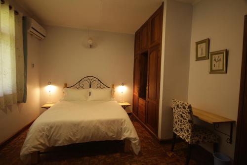 a bedroom with a bed and two tables and a chair at Boulevard Inn Mt Meru in Arusha