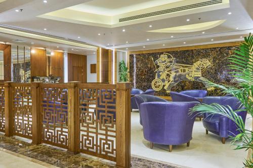 a lobby with purple chairs and a mural at La Roche Hotel in Erbil