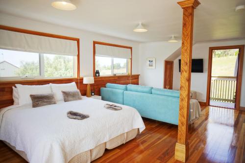 um quarto com uma cama grande e um sofá azul em @ the beach & not quite @ the beach Holiday Cottages - Stanley em Stanley