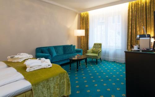 a hotel room with a bed and a blue couch at Hotel Bristol in Oslo