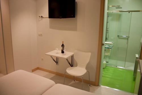 a bathroom with a table and a chair and a shower at Pensión C7 in San Sebastián