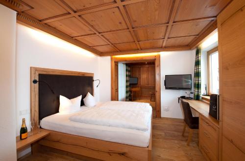a bedroom with a bed and a desk and a television at Hotel St Hubertus in Egg