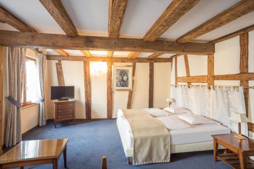 a bedroom with a bed and a table and a tv at Hostellerie Schwendi in Kientzheim