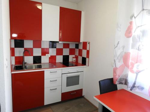 a small kitchen with red and white tiles on the wall at Apartmaji Sobe Zvezda in Pobegi