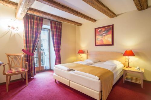a bedroom with a large bed and a chair at Hostellerie Schwendi in Kientzheim