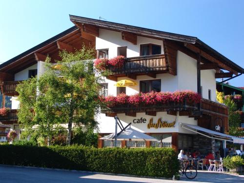 a building with a balcony with flowers on it at Das Landhaus am See in Achenkirch