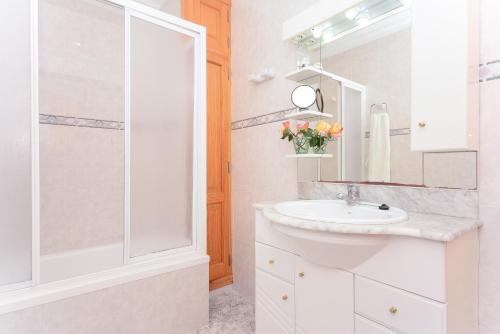 een witte badkamer met een wastafel en een douche bij Pinya in Port d'Alcudia