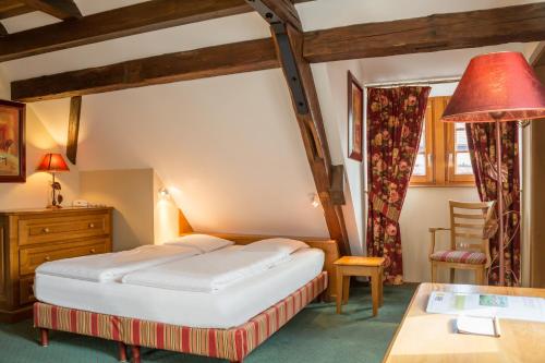 a hotel room with a bed and a desk at Hostellerie Schwendi in Kientzheim