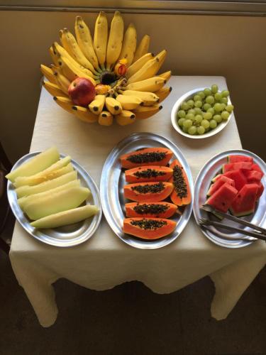 una mesa con platos de frutas y hortalizas. en Hotel Raio de Sol en Guarapari