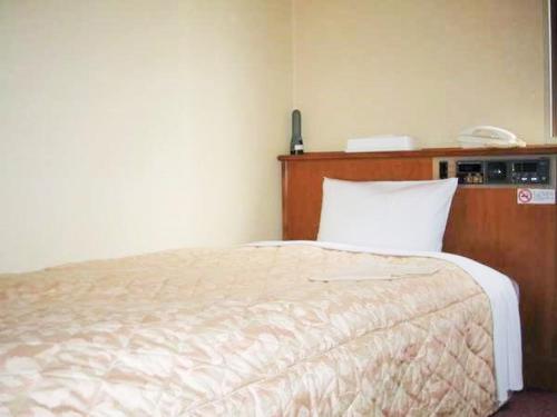 a bedroom with a bed and a phone on the wall at Nishishinjuku Green Hotel in Tokyo