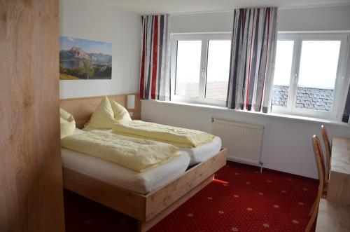 a bedroom with two beds and two windows at Gasthof-Pension Urzn in Altmünster