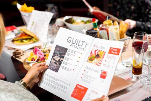 a person holding up a menu at a table with food at Novotel Brussels City Centre in Brussels