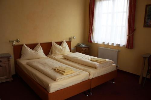a bedroom with two beds with white sheets and a window at Autobahnrestaurant & Motorhotel Zöbern in Zöbern