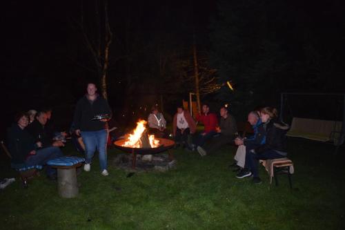 a group of people sitting around a fire at night at Pension Lachmann in Pfaffendorf